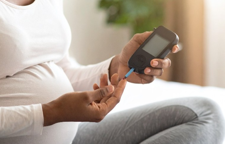 Pregnant patient checking her blood glucose at home